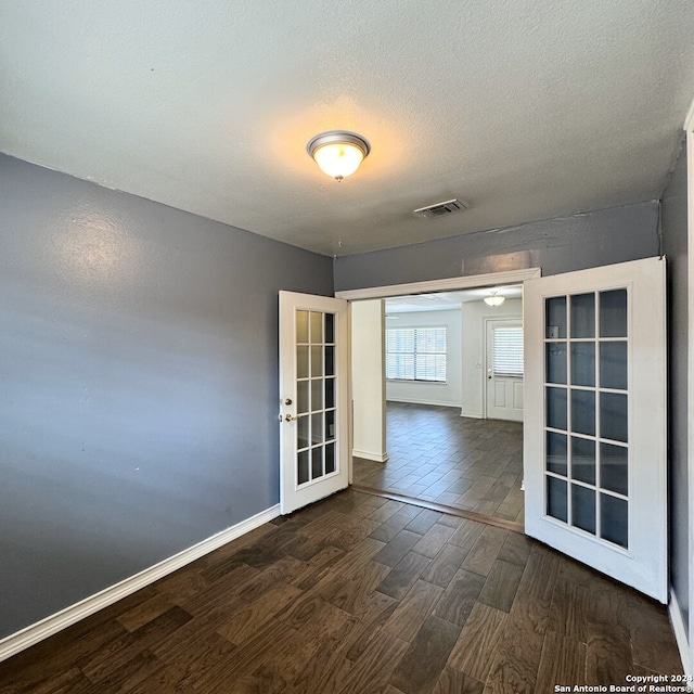 spare room featuring french doors, dark hardwood / wood-style floors, and a textured ceiling