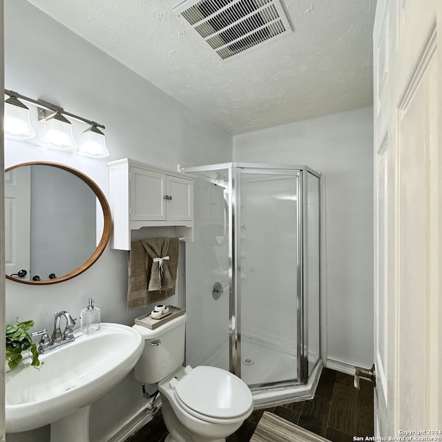 bathroom featuring hardwood / wood-style floors, sink, a textured ceiling, toilet, and a shower with door