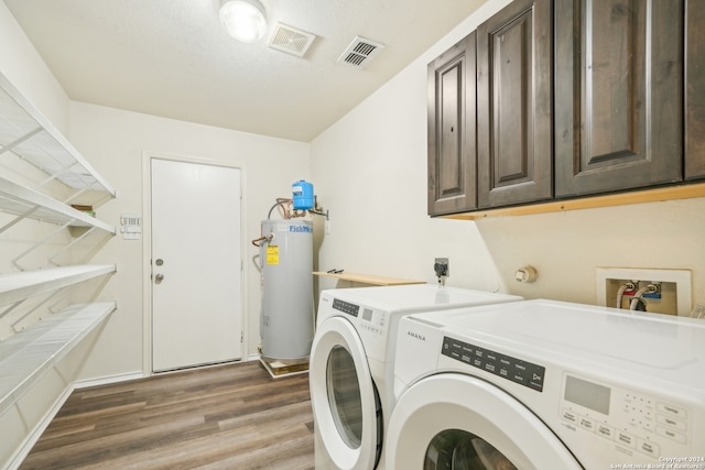 laundry room with cabinets, water heater, washing machine and clothes dryer, and hardwood / wood-style floors