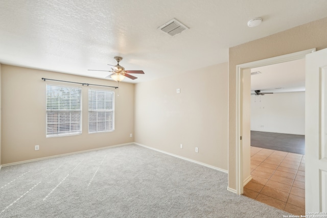 spare room featuring a textured ceiling, light colored carpet, and ceiling fan