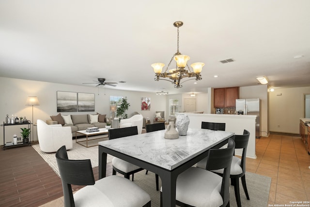 dining room with ceiling fan with notable chandelier and light hardwood / wood-style flooring