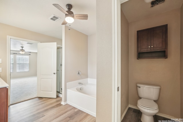 bathroom featuring toilet, wood-type flooring, ceiling fan, and a tub