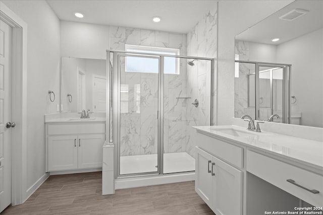 bathroom with vanity, a shower with shower door, and wood-type flooring