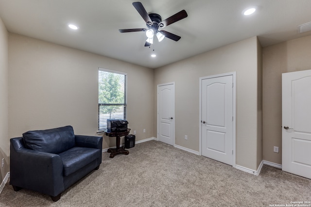 living area with ceiling fan and light colored carpet