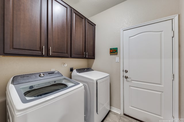 clothes washing area featuring cabinets, washer and dryer, a textured ceiling, and light tile patterned flooring