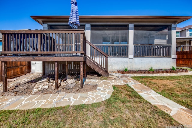 back of property featuring a yard, a sunroom, and a deck