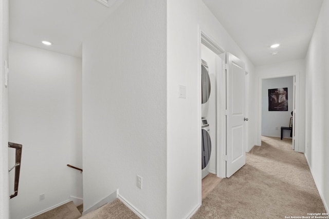 hall featuring light carpet and stacked washer / drying machine