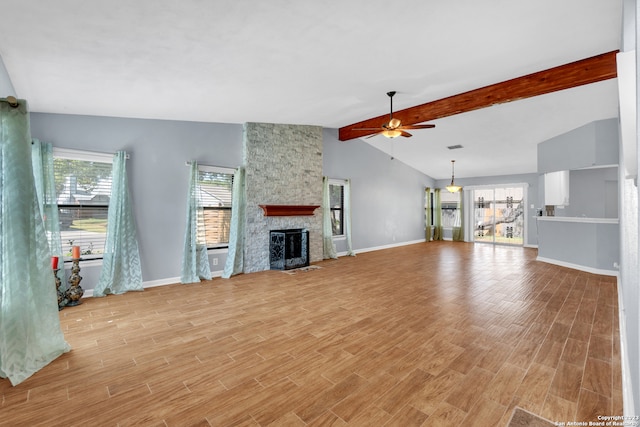 unfurnished living room with a fireplace, light hardwood / wood-style floors, vaulted ceiling with beams, and a healthy amount of sunlight