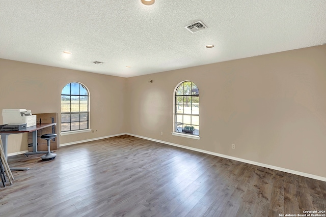 unfurnished office featuring wood-type flooring and a textured ceiling