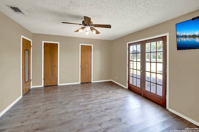 empty room featuring wood-type flooring, french doors, and a textured ceiling