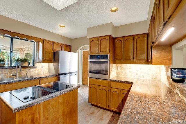 kitchen featuring appliances with stainless steel finishes, sink, light hardwood / wood-style floors, and tasteful backsplash