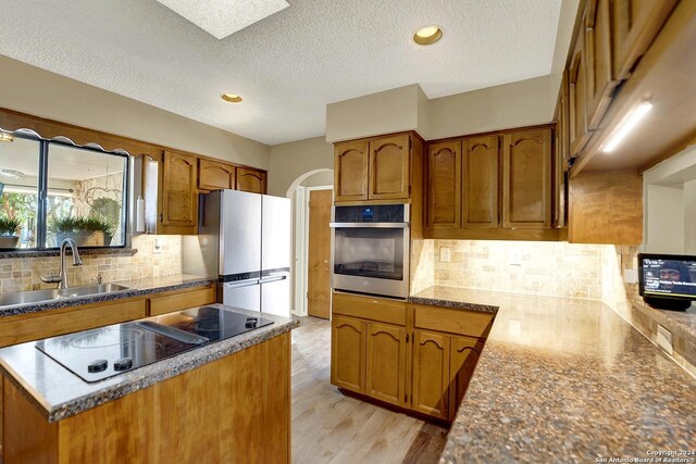 6776 Green Valley Rd, Cibolo, TX 78108 - kitchen with brown cabinetry, appliances with stainless steel finishes, a sink, and a kitchen island