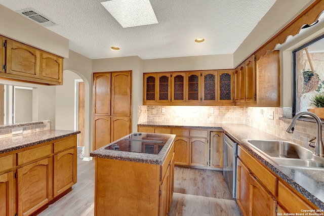 kitchen with a center island, sink, light hardwood / wood-style floors, a skylight, and a textured ceiling