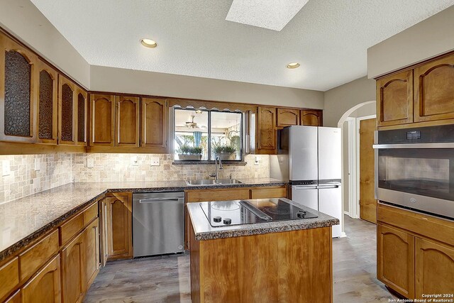 6776 Green Valley Rd, Cibolo, TX 78108 - kitchen featuring black electric cooktop, visible vents, a sink, arched walkways, and a kitchen island