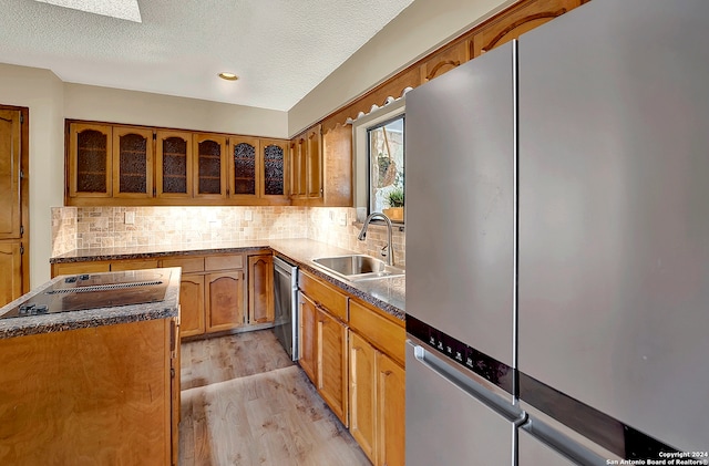 kitchen featuring light hardwood / wood-style floors, sink, stainless steel appliances, and a textured ceiling