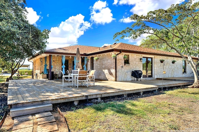 rear view of house featuring a wooden deck and a lawn