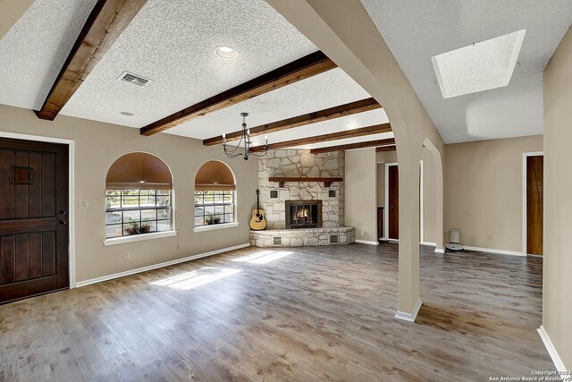 6776 Green Valley Rd, Cibolo, TX 78108 - unfurnished living room featuring a textured ceiling, visible vents, an inviting chandelier, beamed ceiling, and a stone fireplace