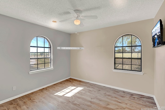 empty room with ceiling fan, light hardwood / wood-style floors, and a textured ceiling