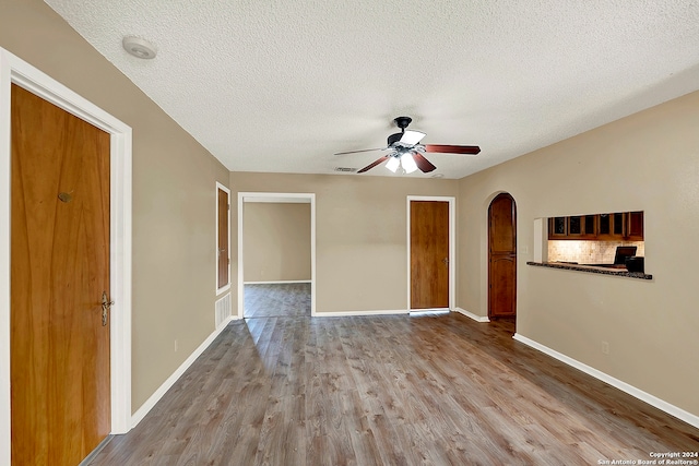 empty room with ceiling fan, a textured ceiling, and light hardwood / wood-style flooring