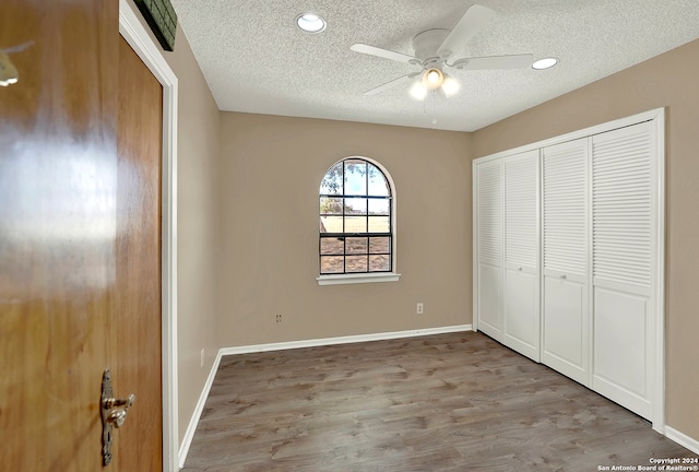 unfurnished bedroom with a textured ceiling, ceiling fan, a closet, and light hardwood / wood-style flooring