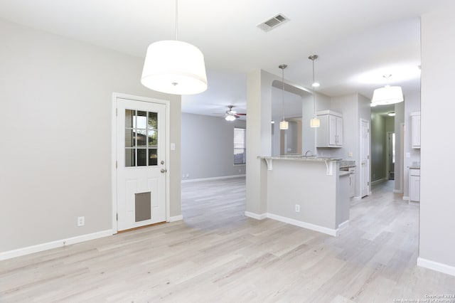 kitchen featuring pendant lighting, light wood-type flooring, kitchen peninsula, and white cabinetry