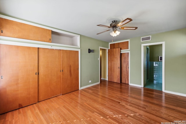 unfurnished bedroom featuring ceiling fan, hardwood / wood-style floors, and connected bathroom