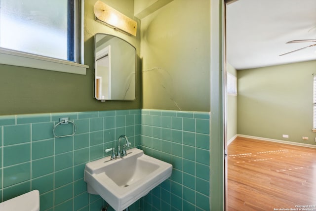 bathroom with hardwood / wood-style flooring, tile walls, sink, and a healthy amount of sunlight