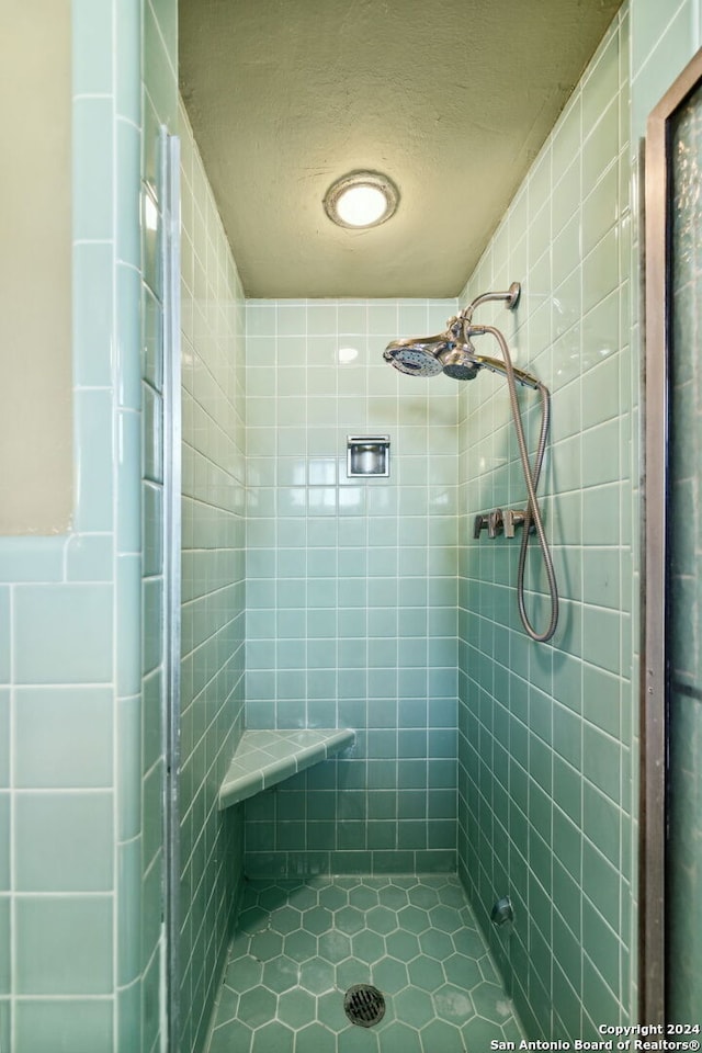 bathroom with a tile shower, tile patterned flooring, tile walls, and a textured ceiling