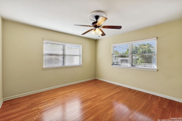 spare room with a healthy amount of sunlight, ceiling fan, and hardwood / wood-style floors