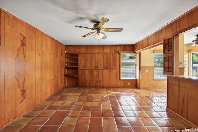 spare room with wood walls, tile patterned flooring, and ceiling fan