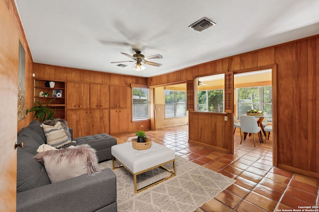 tiled living room with ceiling fan and wooden walls