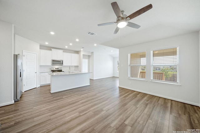 unfurnished living room with light wood-type flooring, ceiling fan, and sink