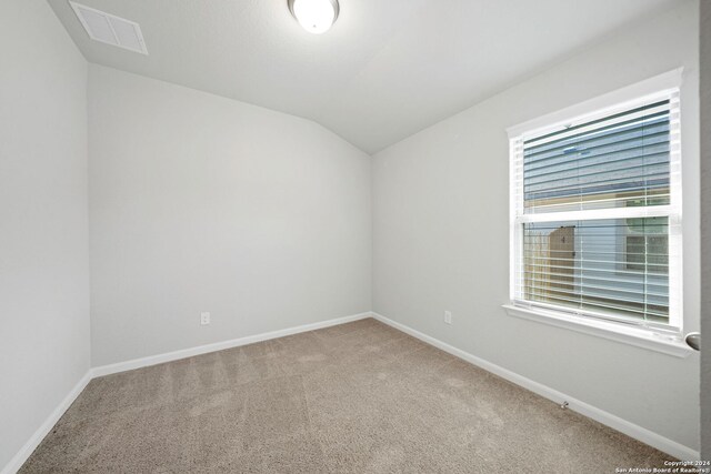 spare room featuring vaulted ceiling and carpet flooring