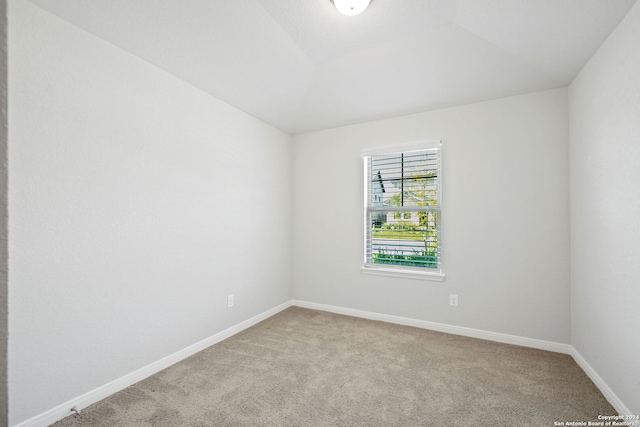 carpeted empty room with lofted ceiling