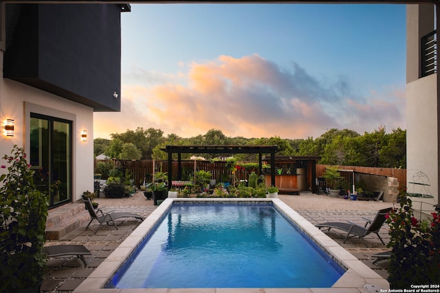 pool at dusk featuring a pergola and a patio