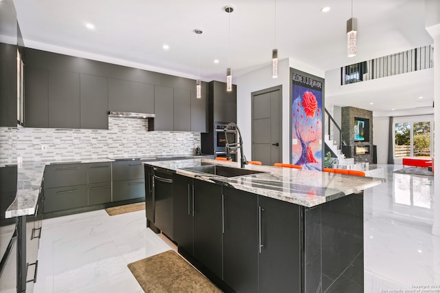 kitchen featuring pendant lighting, black appliances, sink, and a spacious island