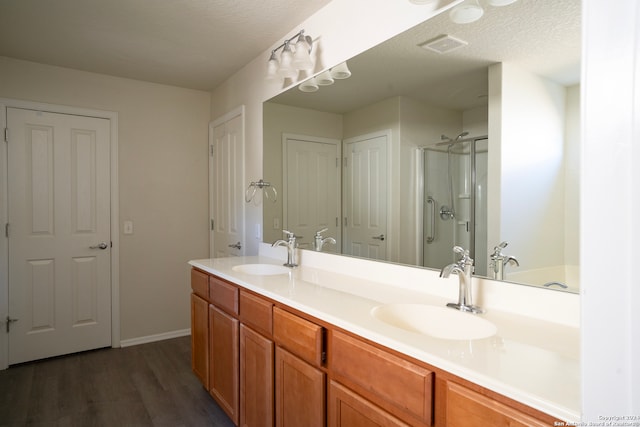 bathroom featuring hardwood / wood-style flooring, vanity, walk in shower, and a textured ceiling