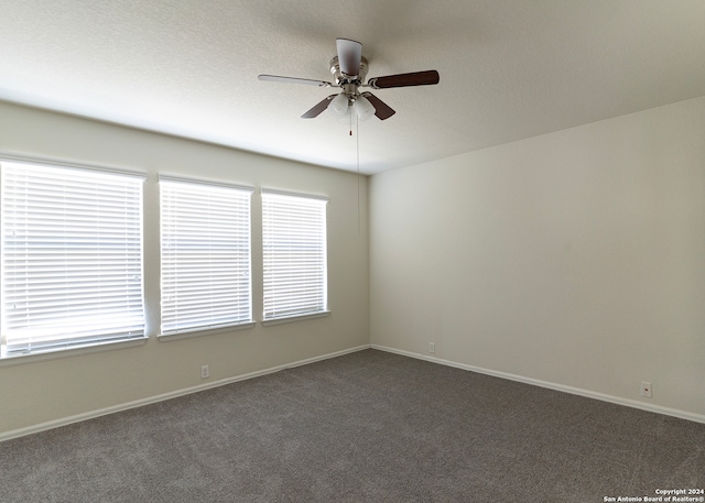 spare room with ceiling fan and dark colored carpet