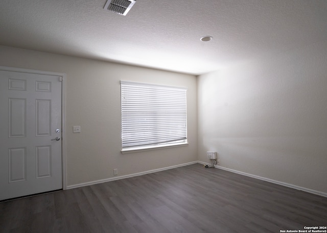 spare room with dark hardwood / wood-style flooring and a textured ceiling