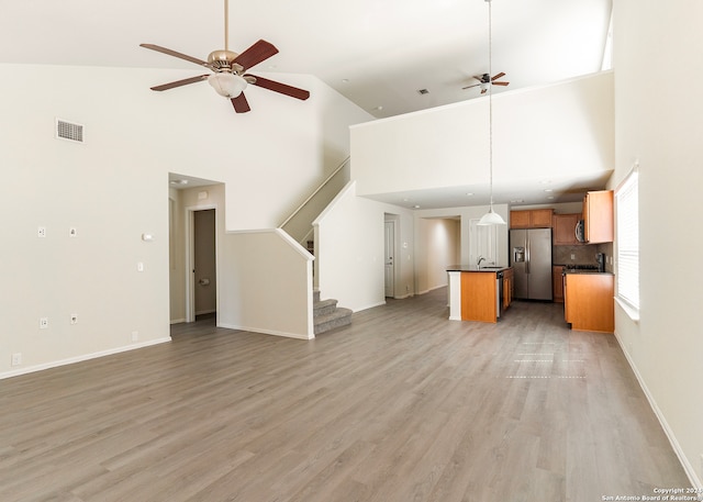 unfurnished living room with ceiling fan, light hardwood / wood-style floors, and high vaulted ceiling