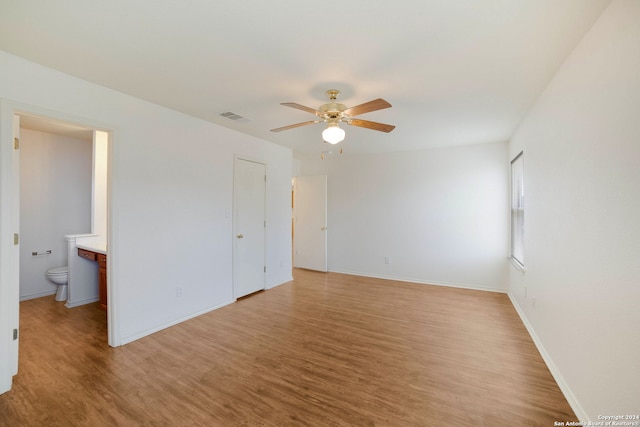 unfurnished bedroom with ceiling fan, a closet, hardwood / wood-style floors, and connected bathroom