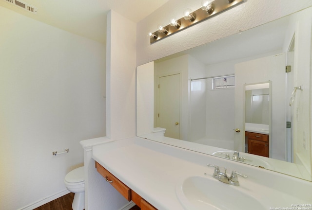 bathroom featuring vanity, a shower, hardwood / wood-style floors, and toilet