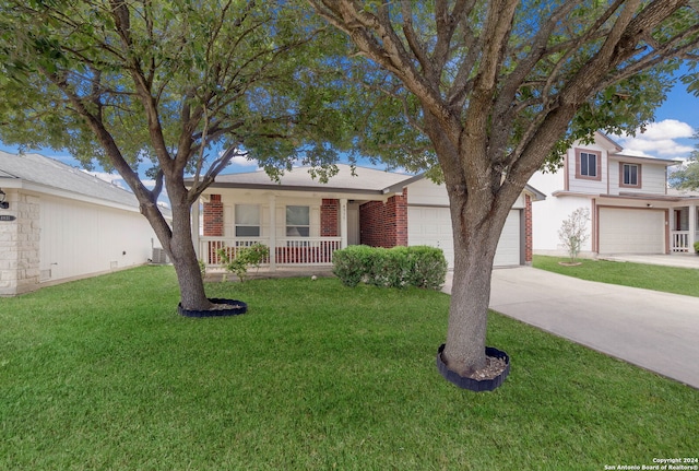 view of front of property with central AC, a porch, a front yard, and a garage