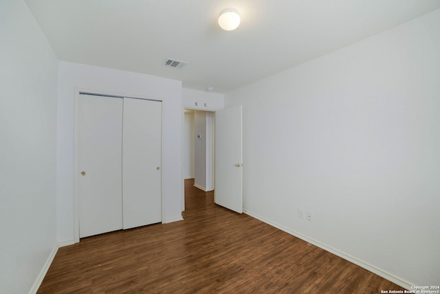 unfurnished bedroom with a closet and dark hardwood / wood-style flooring