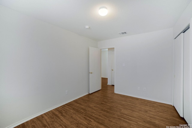 unfurnished bedroom featuring a closet and dark hardwood / wood-style flooring