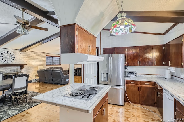 kitchen featuring a stone fireplace, stainless steel appliances, hanging light fixtures, tile counters, and beam ceiling