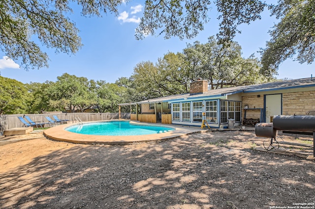 view of swimming pool with a sunroom and a patio