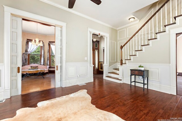 entryway featuring ornamental molding, dark wood-type flooring, and ceiling fan with notable chandelier