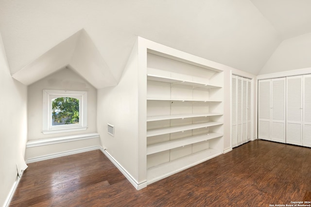 additional living space with dark wood-type flooring, built in features, and vaulted ceiling