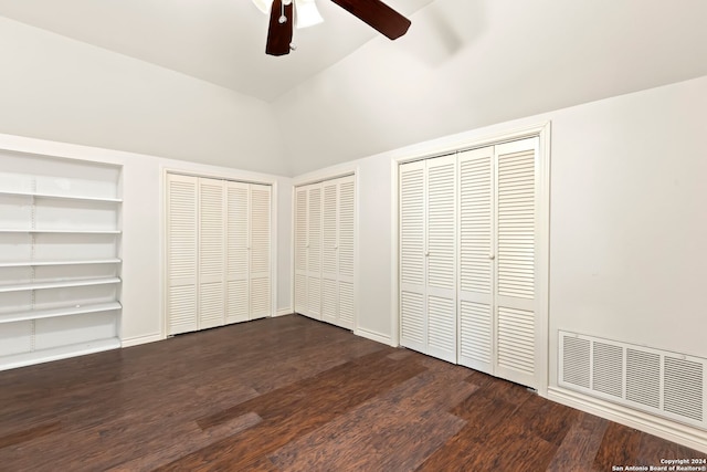 unfurnished bedroom featuring vaulted ceiling, ceiling fan, dark wood-type flooring, and two closets